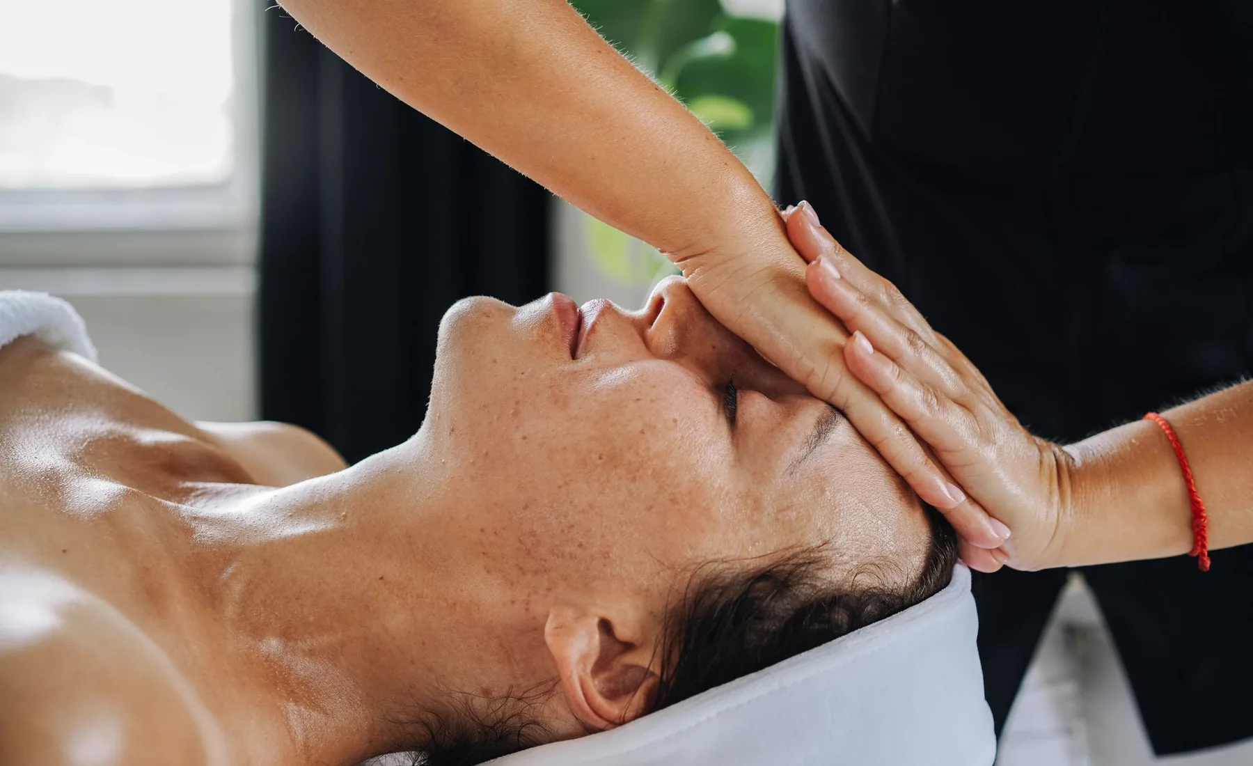 Terapeuta dando un masaje facial en una sala de spa con luz cálida